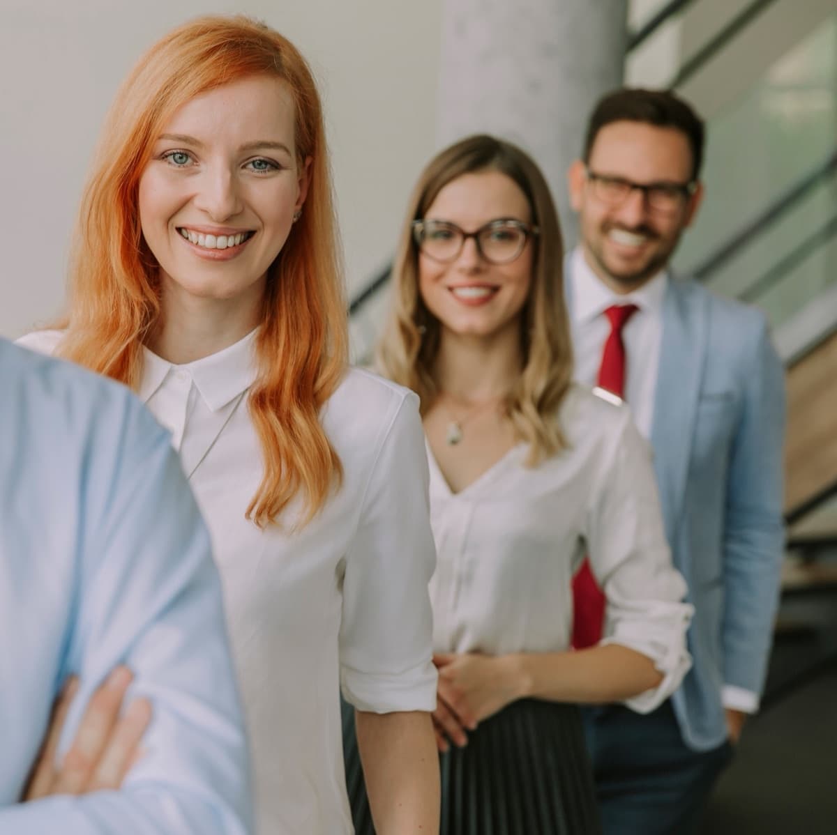 Three smiling colleagues standing together in an office